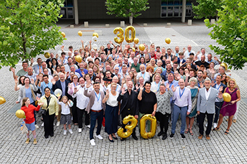 Foto: Aufnahme einer großen Gruppe von Personen und einer großen goldenen Dreißig