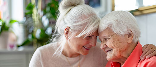 Symbolbild: Eine Frau mittleren Alters hält eine Seniorin im Arm