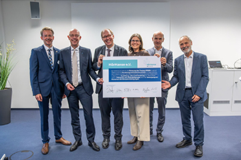 Foto der Gründungsmitglieder der HörHanse, die eine überdimensionale, symbolische Gründungsurkunde in den Händen halten