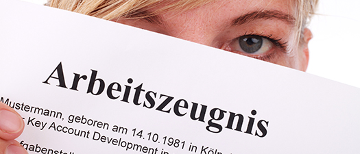 Bildbeschreibung: Man sieht ein Blatt Papier mit dem Wort "Arbeitszeugnis". Dahinter versteckt sich eine Person. Man sieht nur ihr Auge hinter dem Blatt Papier.