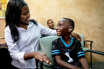 Bildbeschreibung: Der kleine Junge Kaysha bekommt von der Hörakustikerin Precious Mumba sein Hörgerät angepasst.