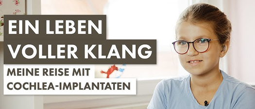 Bildbeschreibung: Das Bild zeigt einen Ausschnitt aus dem Film Meine Reise mit Cochlea-Implantaten. Darauf abgebildet ist die Protagonistin, die elfjährige Lena Pohl. Ihr Cochlea-Implantat ist durch die Haare verdeckt. Lena trägt eine Brille und ein hellblaues T-Shit sowie Ohrstecker, sie lächelt. Ihre Haare sind zu einem Zopf zusammengebunden.