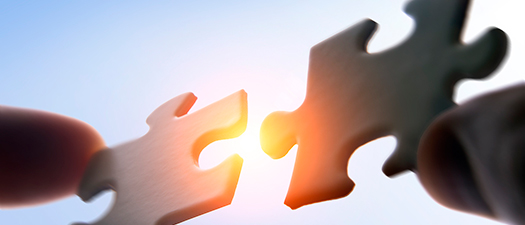 Bildbeschreibung: Auf dem Foto sind zwei Puzzlestücke zu sehen, die zusammengefügt werden.